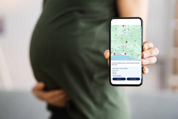 Refer yourself for NHS pregnancy care, a pregnant lady holding her phone with the self referral website
