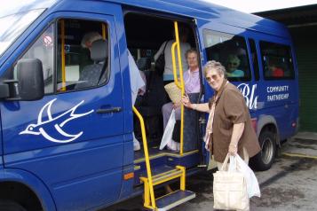 Dial-A-Ride from Community Transport Sussex. Lady with her shopping getting into a blue bus.