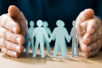 Adult hands surrounding paper cutouts of adult body shapes