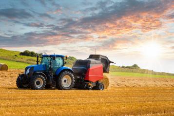 Tractor preparing of straw millstones in a field with sunlight during August