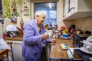 Older lady holding a cup of tea in her kitchen