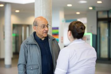 Man standing with staff member in hospital