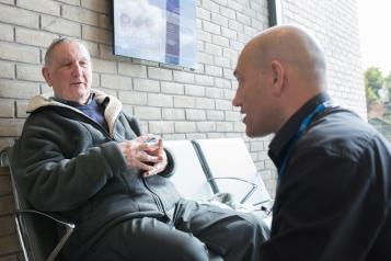 Older man talking to health professional in a waiting room