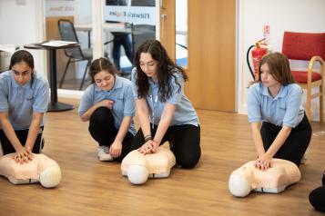 Group of teenagers learning CPR in a classroom