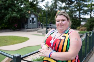 Woman standing against fence, smiling