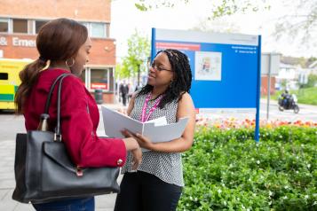 Two people looking at a folder outside a hospital