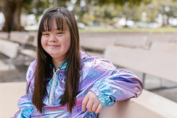 Young woman sitting on bench, smiling