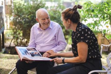 Carer chatting with elderly gentleman while looking at photo album 