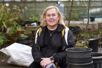 Lady doing some gardening, smiling at the camera. Image from Centre for Ageing Better