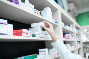 Close up of pharmacist hand taking medicine from the shelf