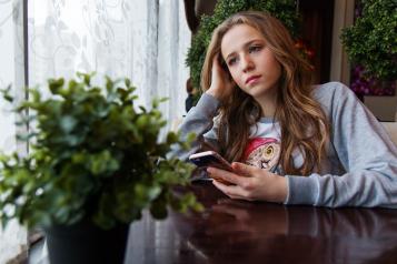 Girl looking sad, holding her phone