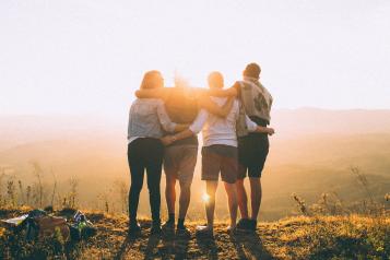 Family hugging facing the sun set overlooking a mountain view 