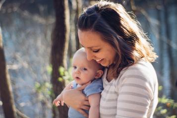 Mum carrying baby near trees