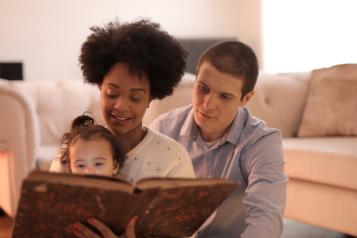 Parents reading a book with their toddler