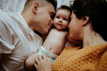 Parents and a baby laying in bed