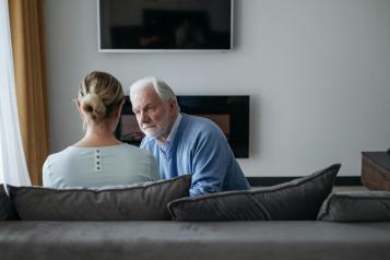 Older male sitting on a sofa chatting to a lady
