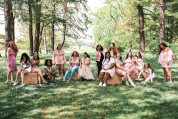 A group of women, different ages in a forest sitting on hay bales