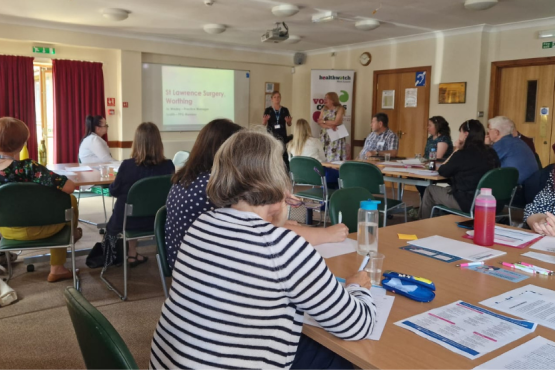 Meeting room filled with people discussing health and social care in Sussex