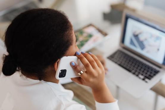 Lady talking on her mobile phone, sitting at her desk with her laptop open