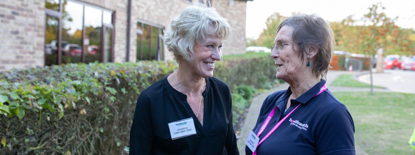 Two ladies from Healthwatch chatting outside a library 