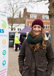 Student volunteer standing infront of a Healthwatch banner