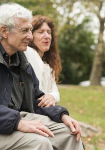 Elderly person sitting on a bench with a friend.